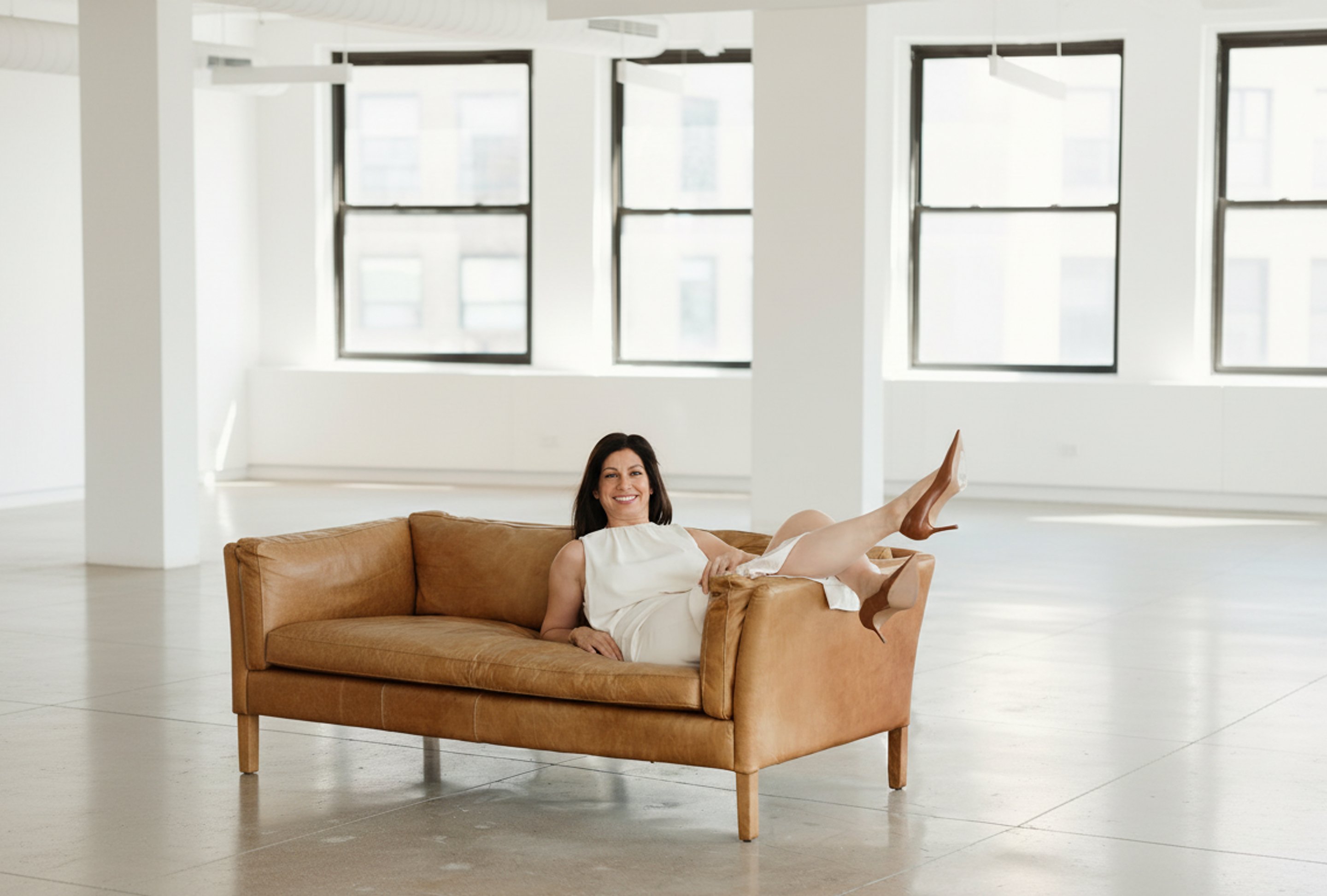 Michal Globen on a leather sofa in a bright New York loft