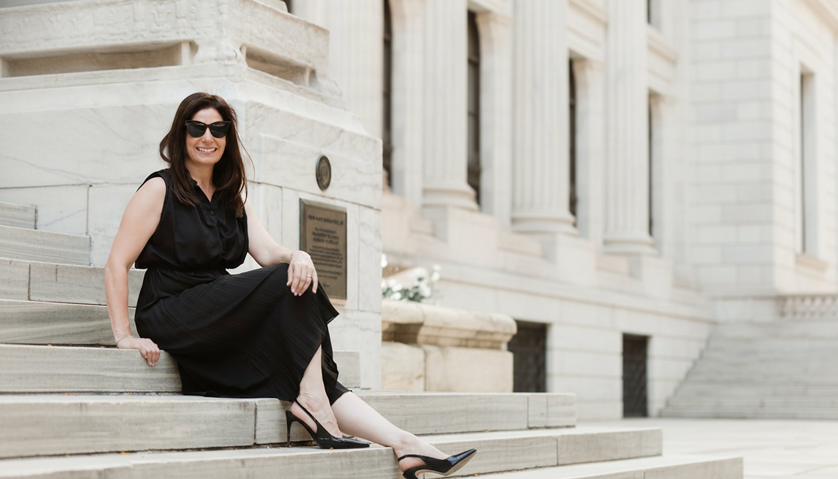 Michal Globen seated on the stone steps of a classic New York building
